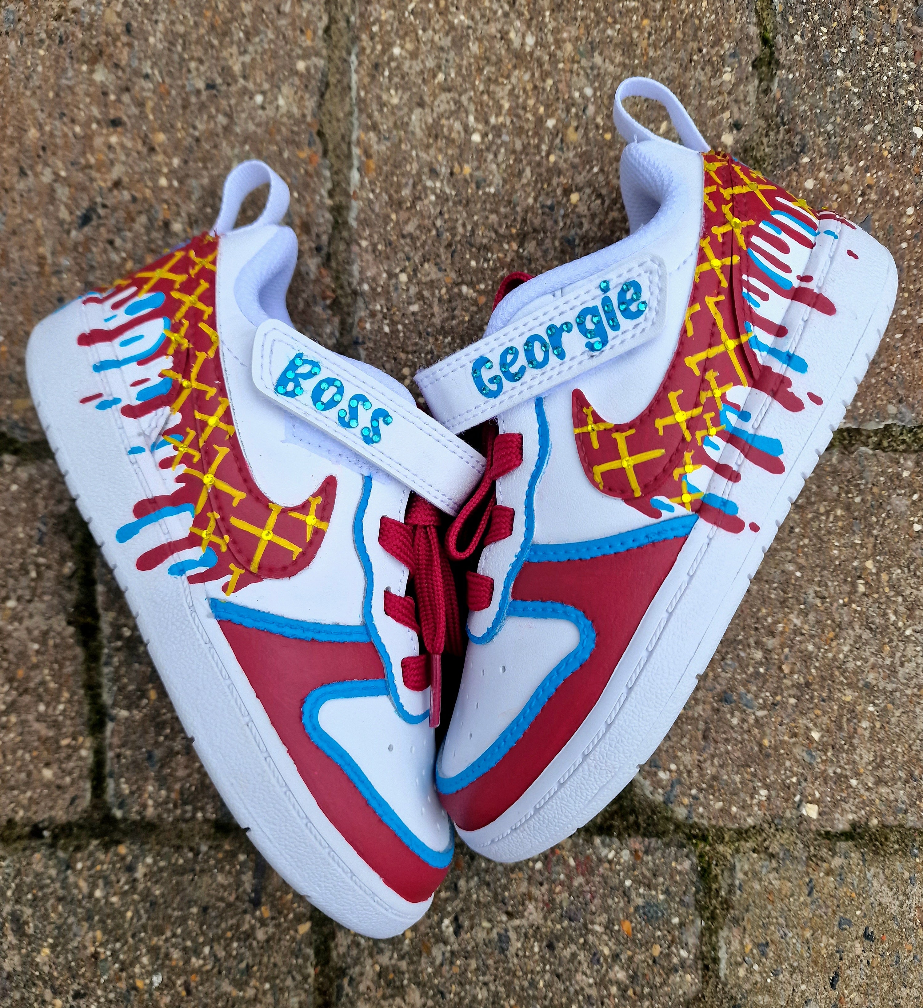 Custom hand-painted baby sneakers inspired by West Ham United, featuring claret and blue color detailing, dripping paint effect, crossed hammers, and personalised names or messages on the straps. Perfect for infant football fans and thoughtful baby gifts.

