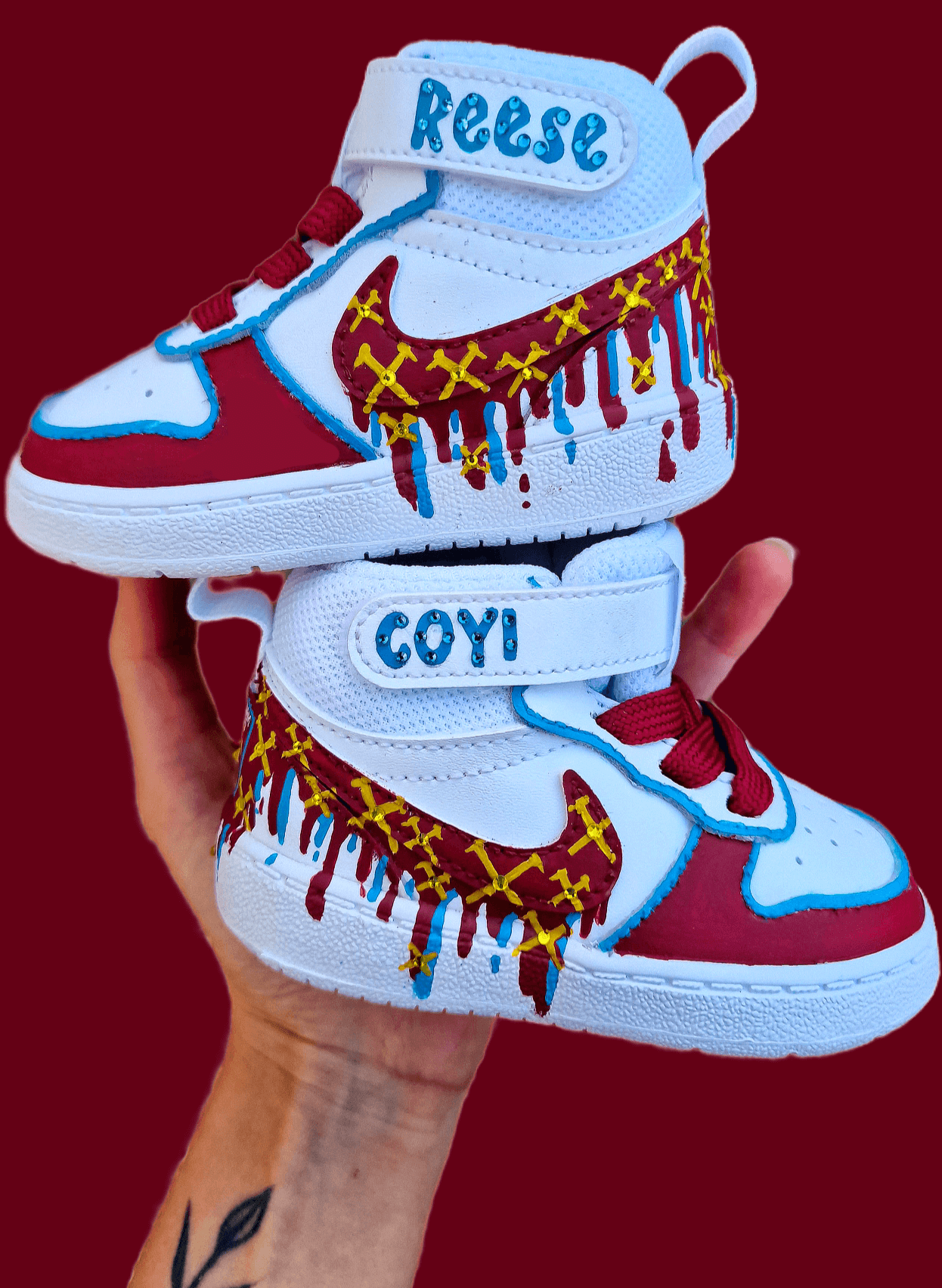 Custom hand-painted baby sneakers inspired by West Ham United, featuring claret and blue color detailing, dripping paint effect, crossed hammers, and personalised names or messages on the straps. Perfect for infant football fans and thoughtful baby gifts.

