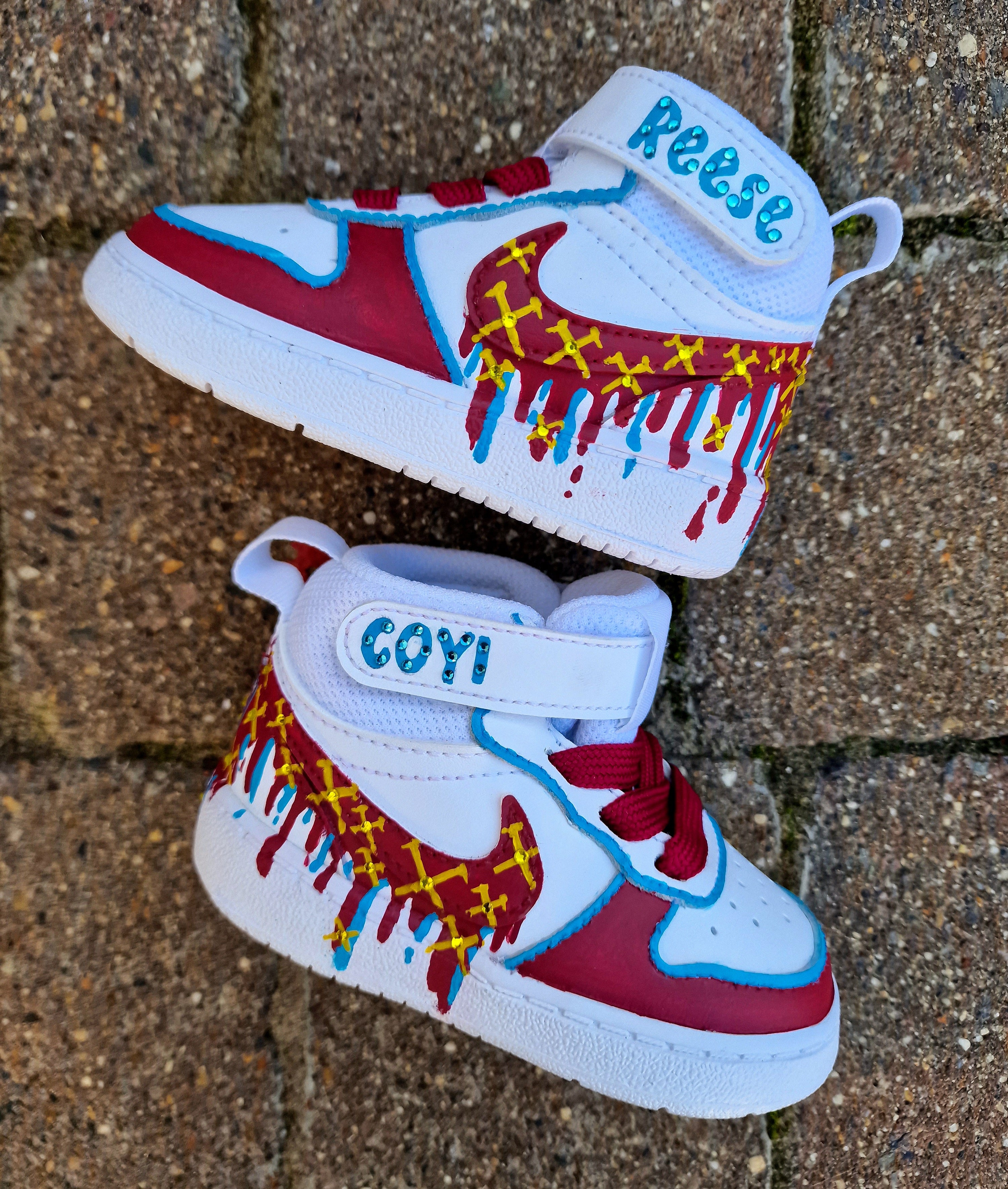 Custom hand-painted baby sneakers inspired by West Ham United, featuring claret and blue color detailing, dripping paint effect, crossed hammers, and personalised names or messages on the straps. Perfect for infant football fans and thoughtful baby gifts.

