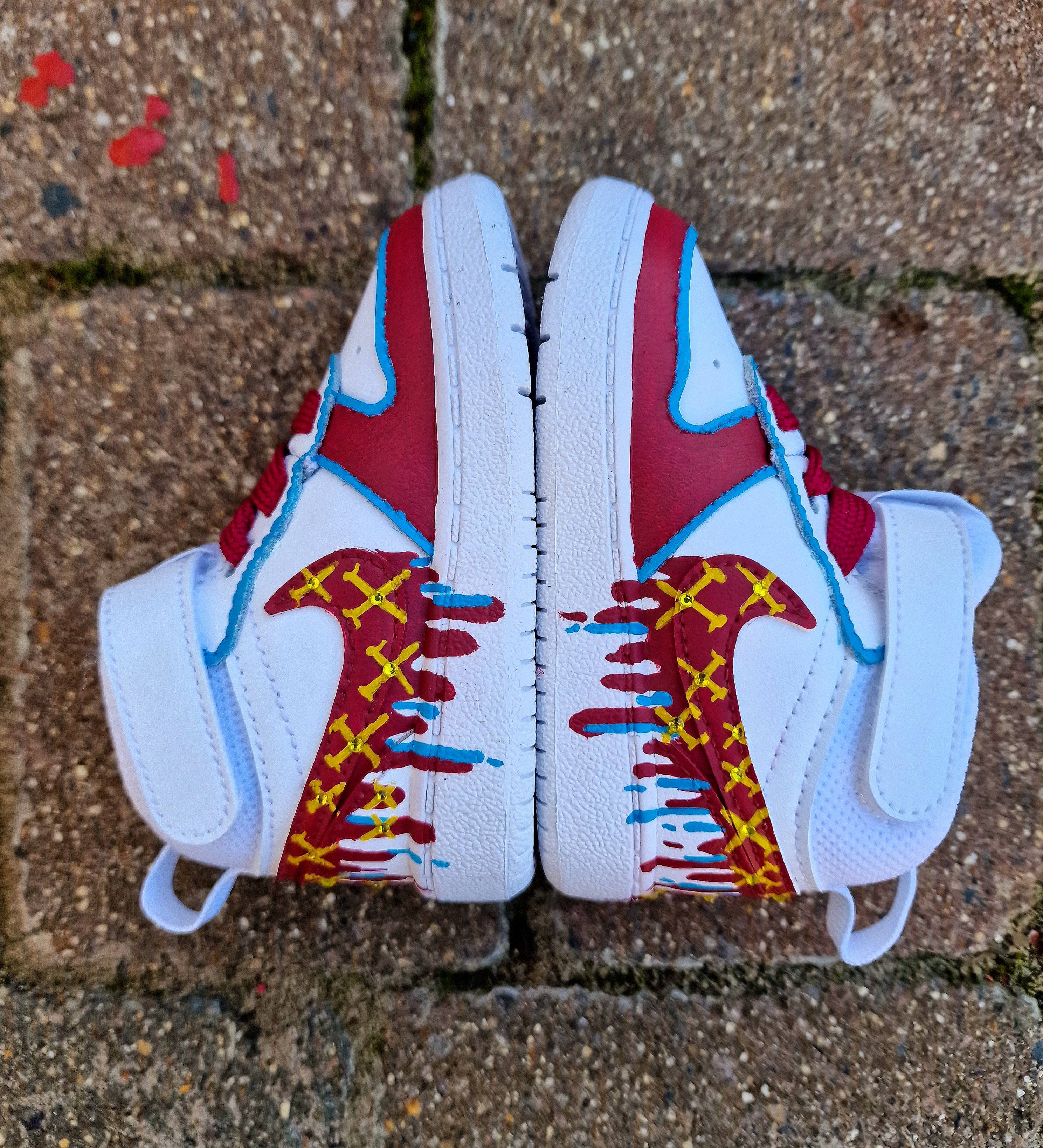 Custom hand-painted baby sneakers inspired by West Ham United, featuring claret and blue color detailing, dripping paint effect, crossed hammers, and personalised names or messages on the straps. Perfect for infant football fans and thoughtful baby gifts.

