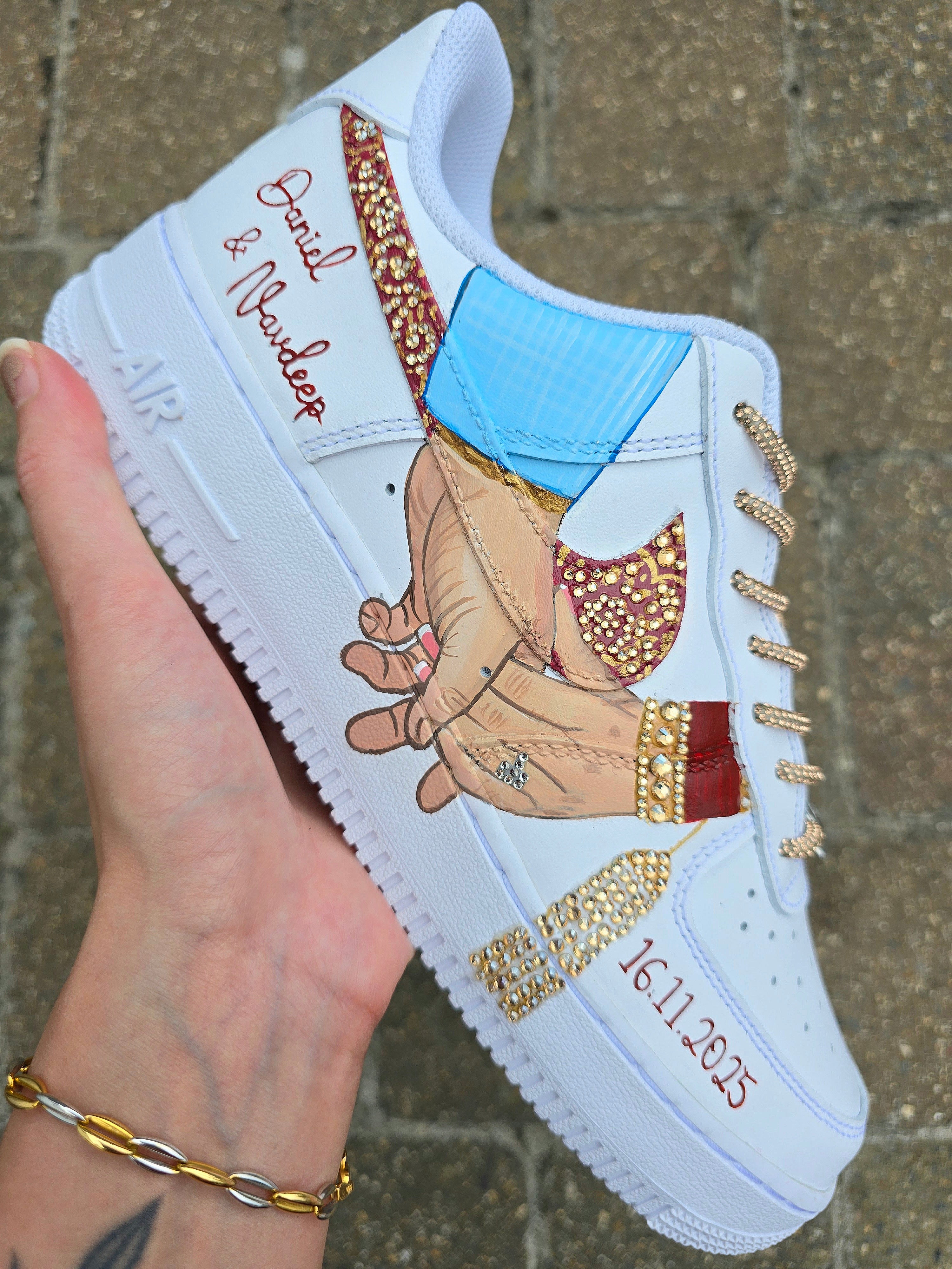 White sneaker with artistic design of hands holding a heart, rhinestones, and text on a textured surface.