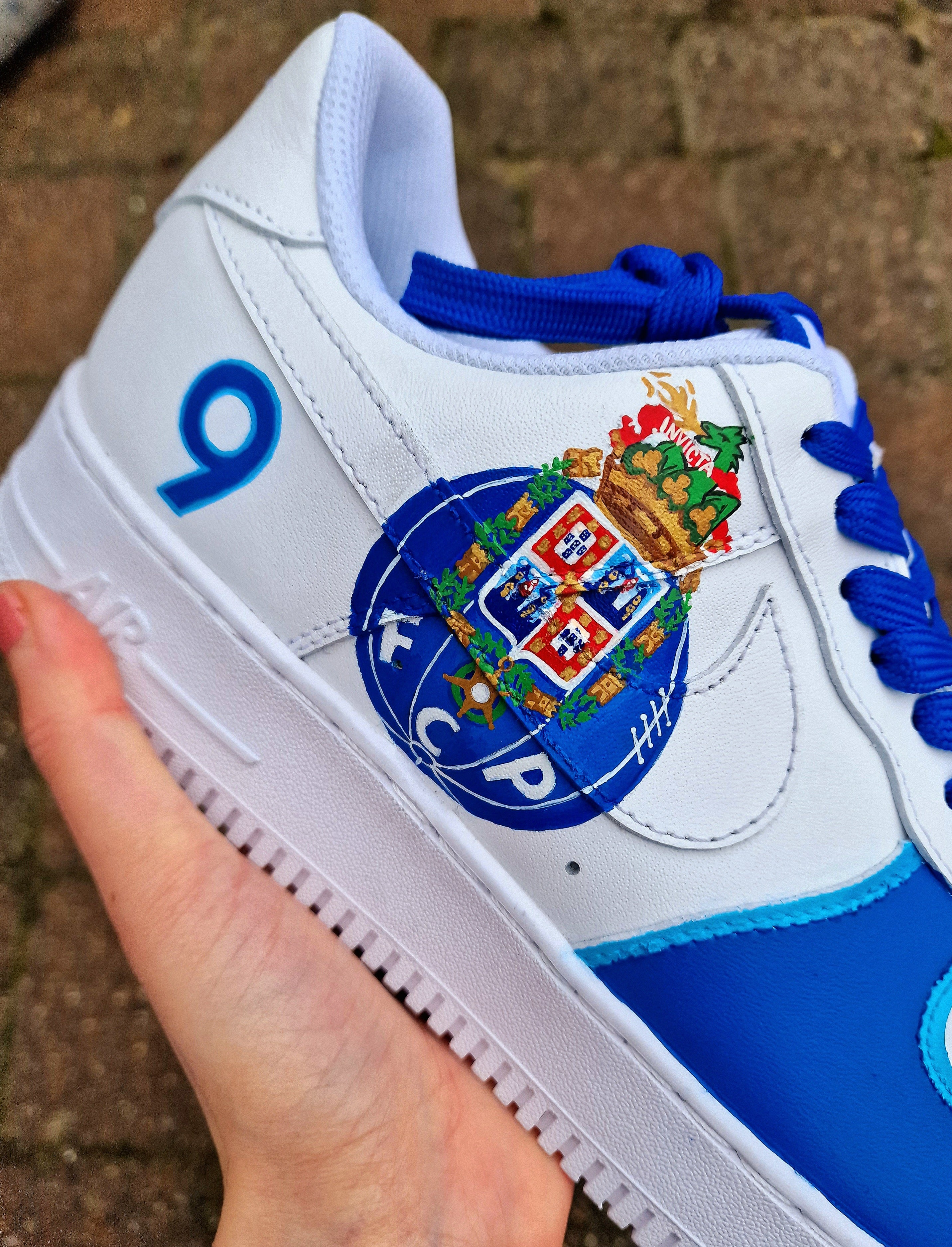 Custom FC Porto Nike Air Force 1 sneakers designed for football fans, featuring hand-painted artwork with the official club crest, blue and white color scheme, dragon mascot, and player number detailing. These one-of-a-kind shoes are crafted using authentic Nike AF1s and painted with weather-resistant leather paints. Perfect for sports lovers and collectors, combining comfort with team spirit.

