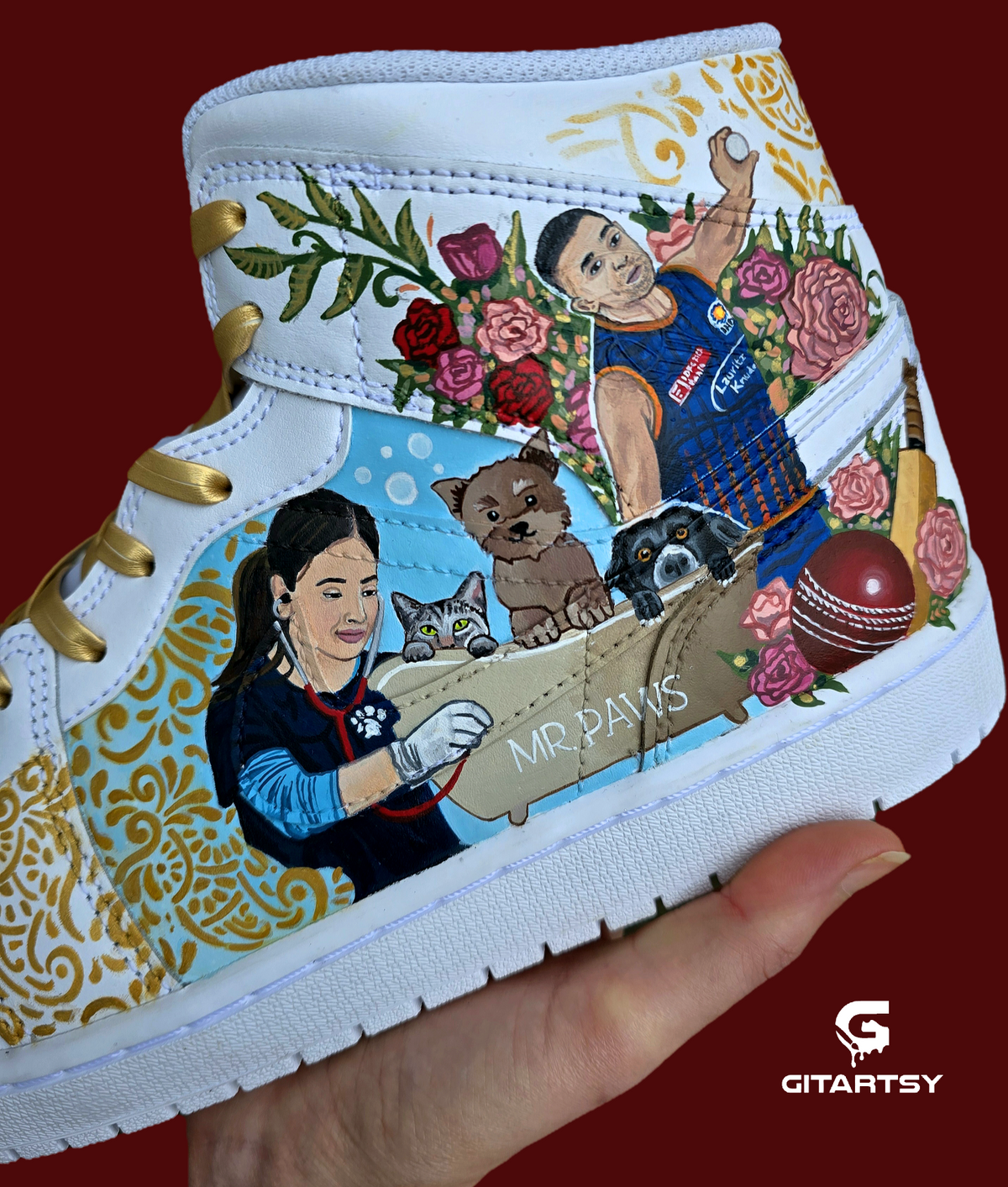 A pair of nike jordan 1 white high-top sneakers with custom illustrations of a couple Arjun Tendulkar and Saaniya Chandhok with gold paisley patterns henna, pets, florals with maroon and blue colour scheme displayed against a dark red background with a GITARTSY logo in the corner.