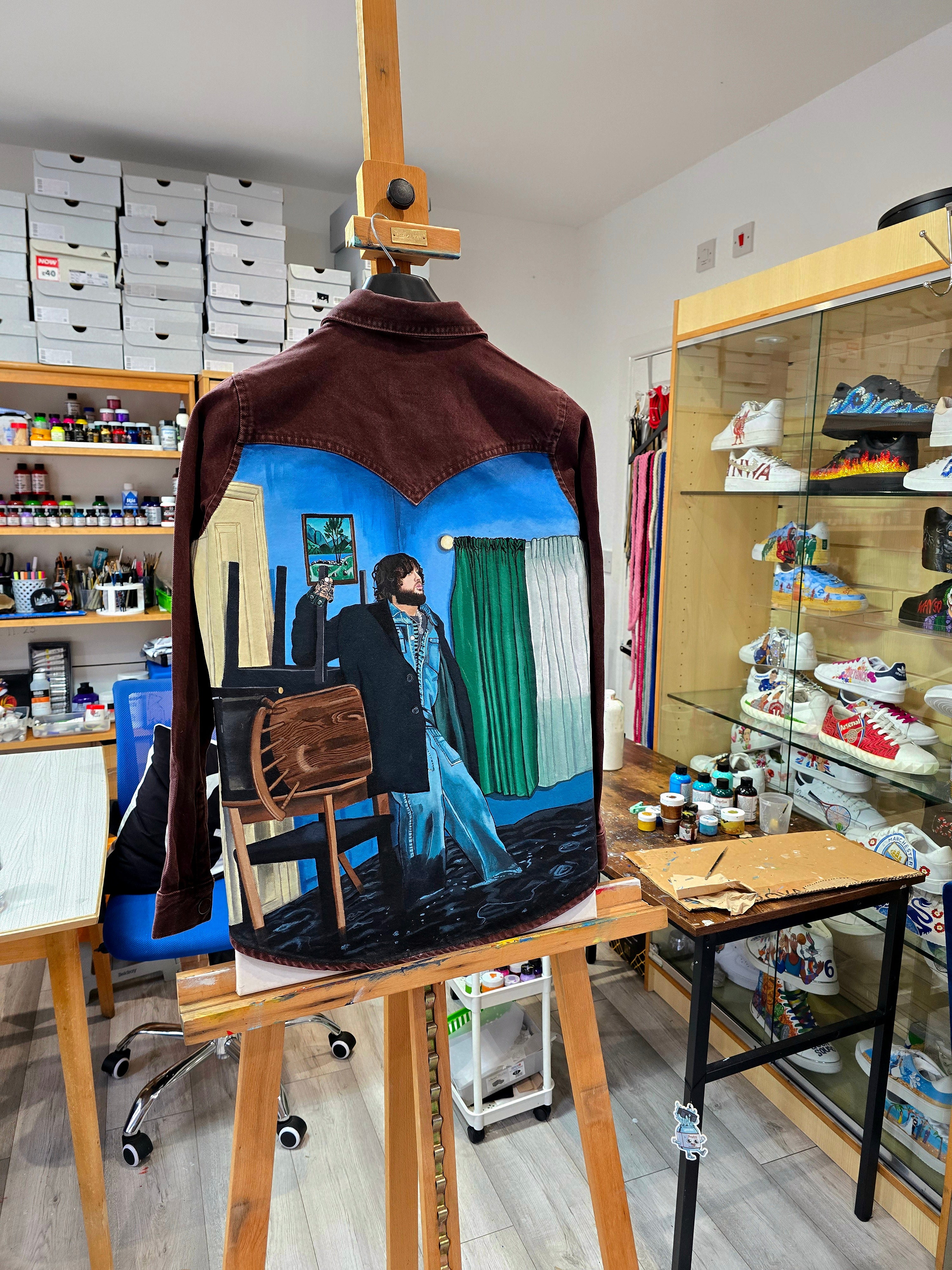 James Arthur Singer Hand Painted Denim Jacket featuring a detailed back artwork of James Arthur in a vibrant indoor scene, painted on a burgundy denim jacket with “Pisces” embroidered on the front, created by Gitartsy using high-quality fabric paints for long-lasting wear.

