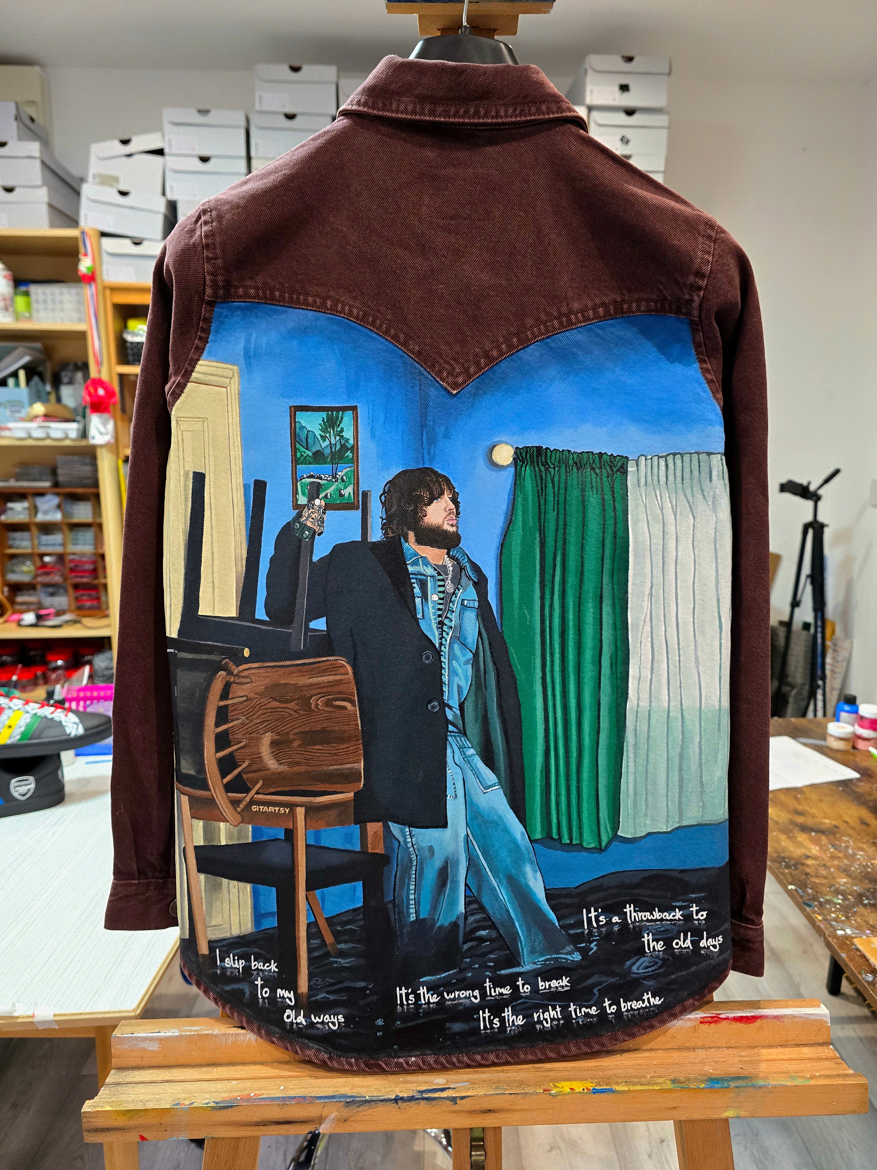 James Arthur Singer Hand Painted Denim Jacket featuring a detailed back artwork of James Arthur in a vibrant indoor scene, painted on a burgundy denim jacket with “Pisces” embroidered on the front, created by Gitartsy using high-quality fabric paints for long-lasting wear.

