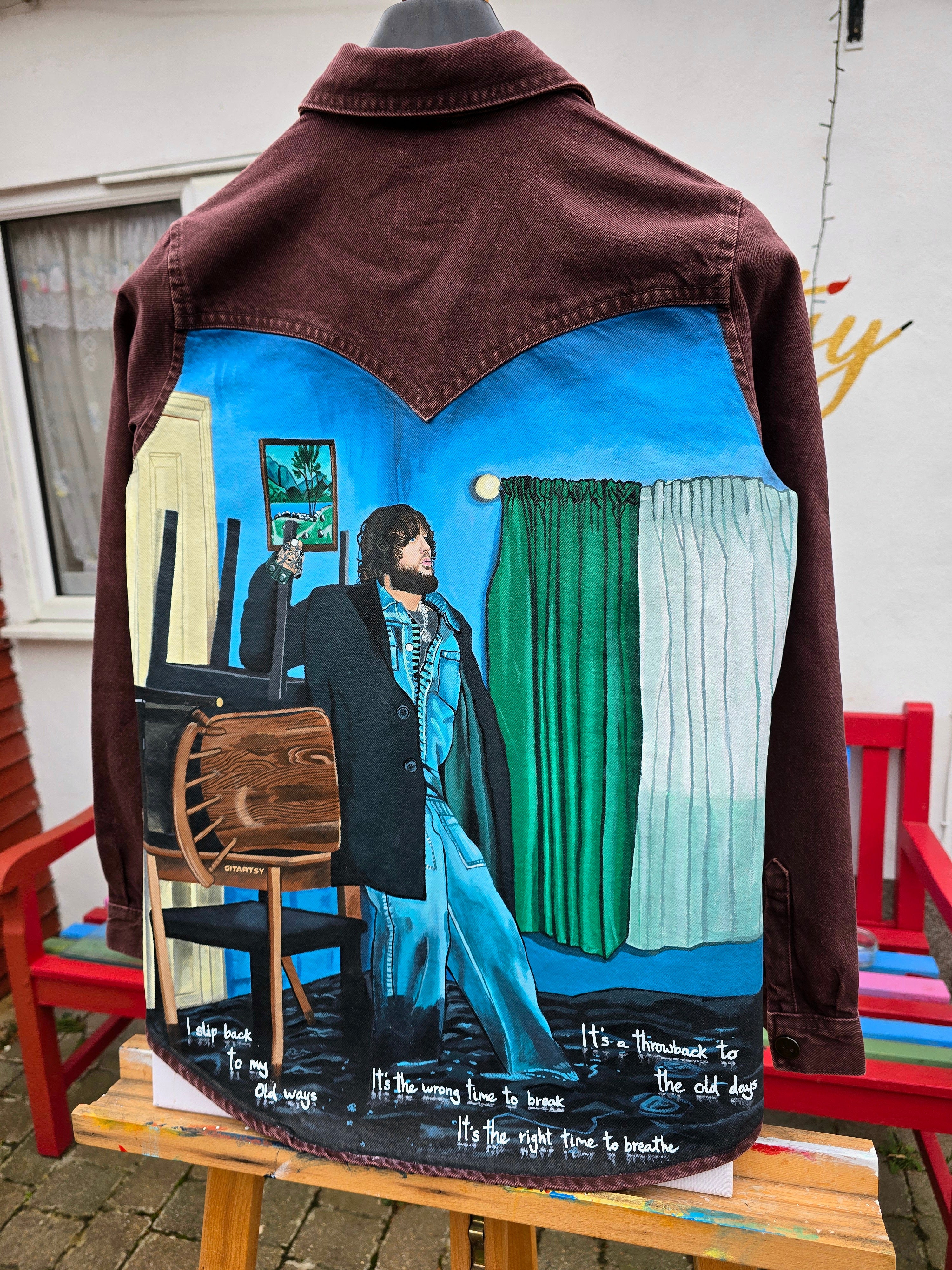 James Arthur Singer Hand Painted Denim Jacket featuring a detailed back artwork of James Arthur in a vibrant indoor scene, painted on a burgundy denim jacket with “Pisces” embroidered on the front, created by Gitartsy using high-quality fabric paints for long-lasting wear.

