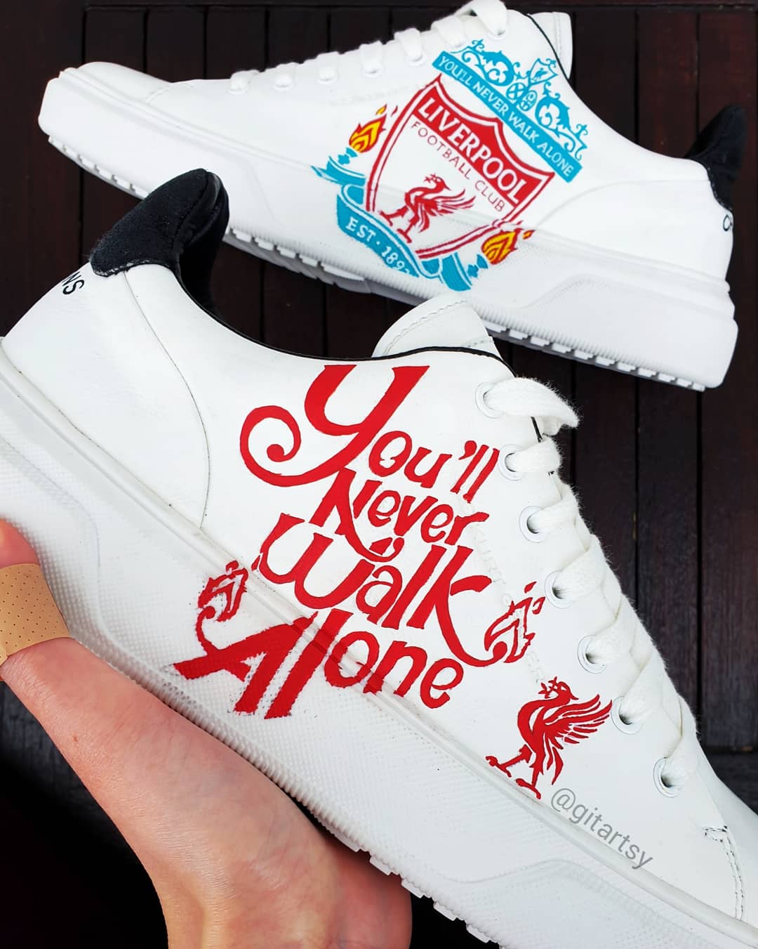Custom Liverpool FC sneakers in white featuring hand-painted artwork with the club crest, Liverbird, “You’ll Never Walk Alone” slogan, and CHAMPIONS 20 detailing. Designed for Liverpool fans, these one-of-a-kind sneakers blend football passion with wearable art. Built on a durable white sole base with red and black accents, ideal for gifting or match day outfits.


