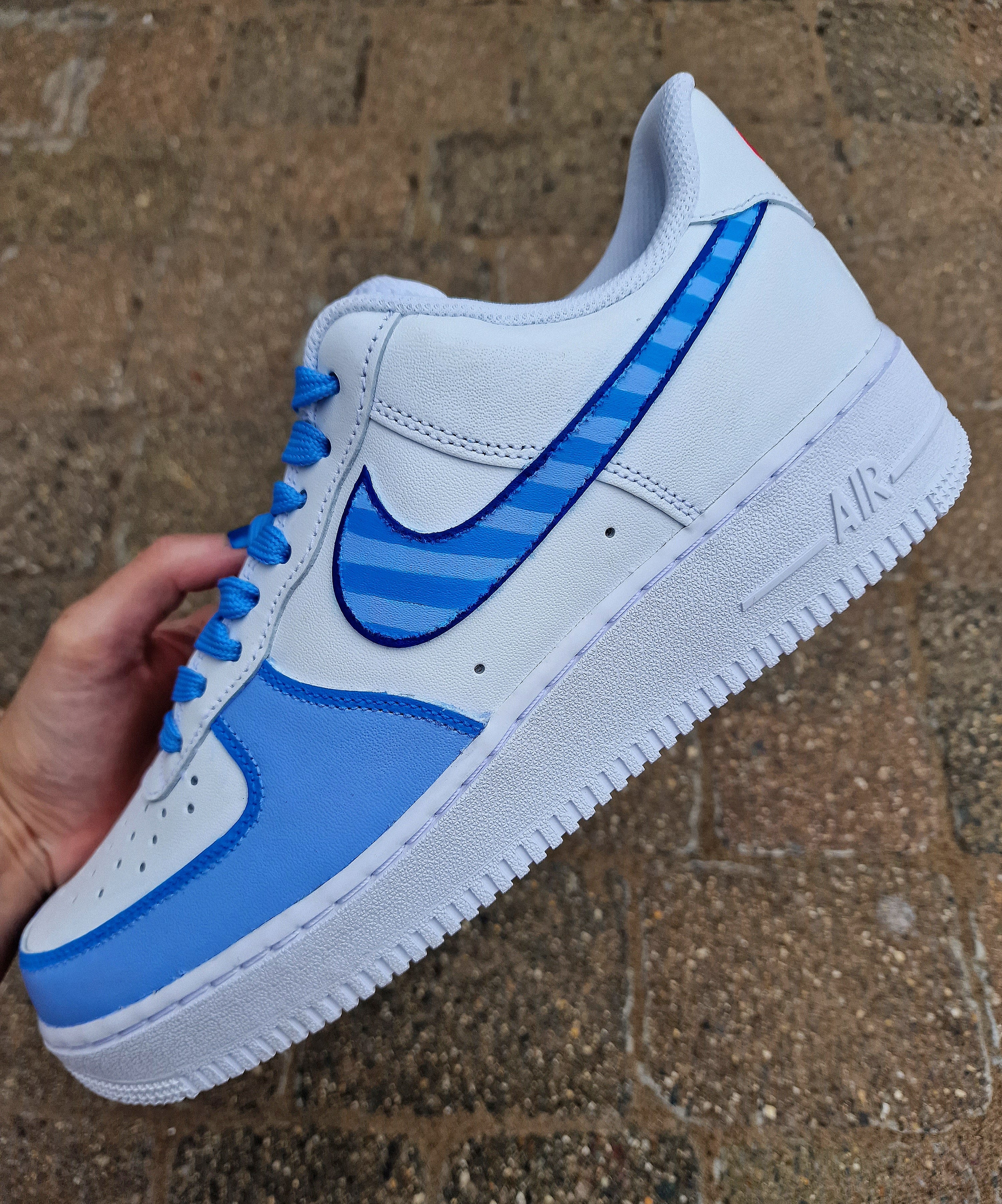 A pair of custom hand-painted Nike Air Force 1 sneakers featuring detailed artwork of the Manchester City Football Club crest, signature blue hues, striped swoosh, and personalized finishing, crafted by Gitartsy for football fans and sneaker collectors.

