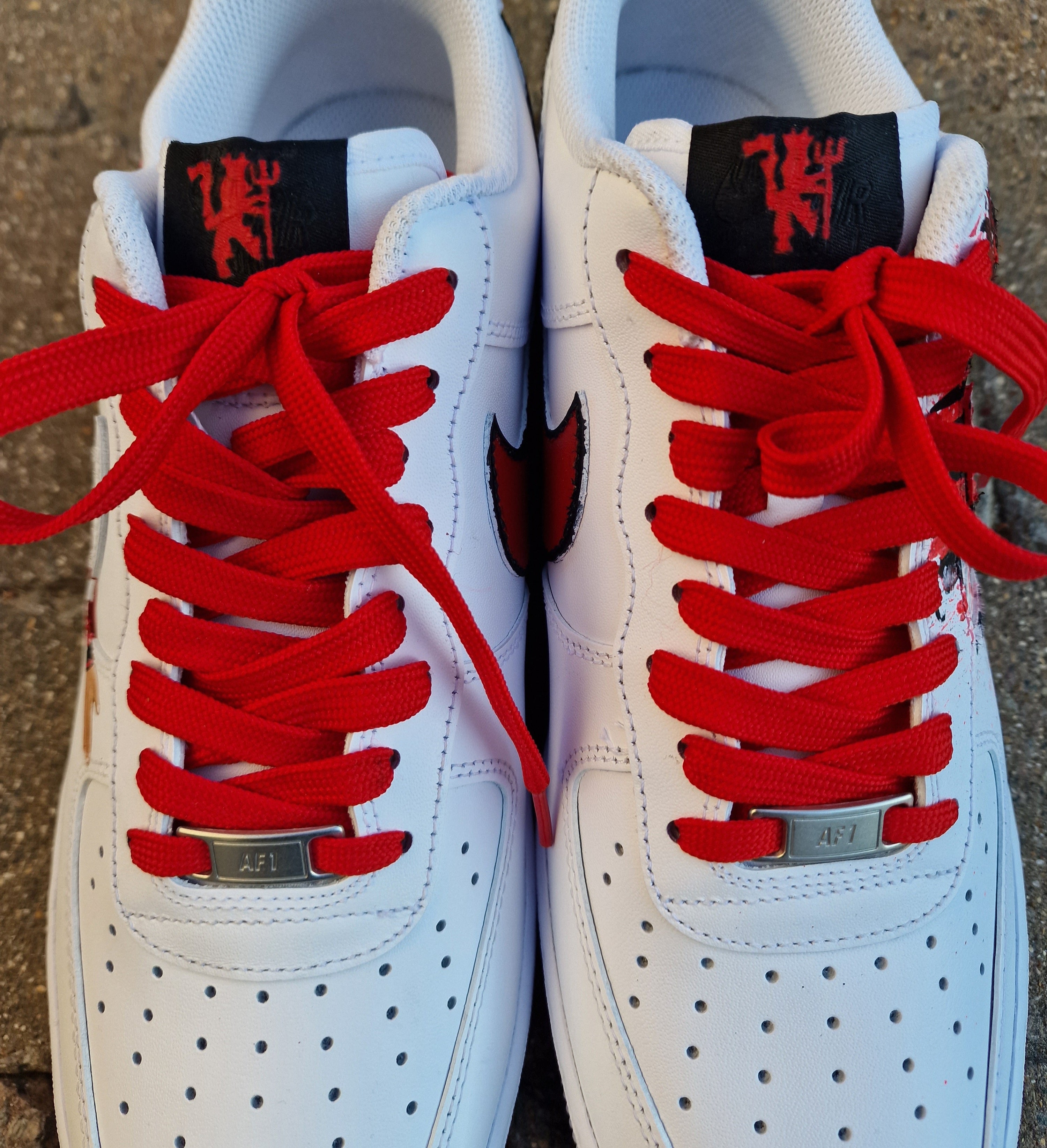 "Custom hand-painted Nike Air Force 1 sneakers featuring Manchester United and Portugal national football team crests, splattered in bold red, green, and black paint with unique details, crafted by Gitartsy."

