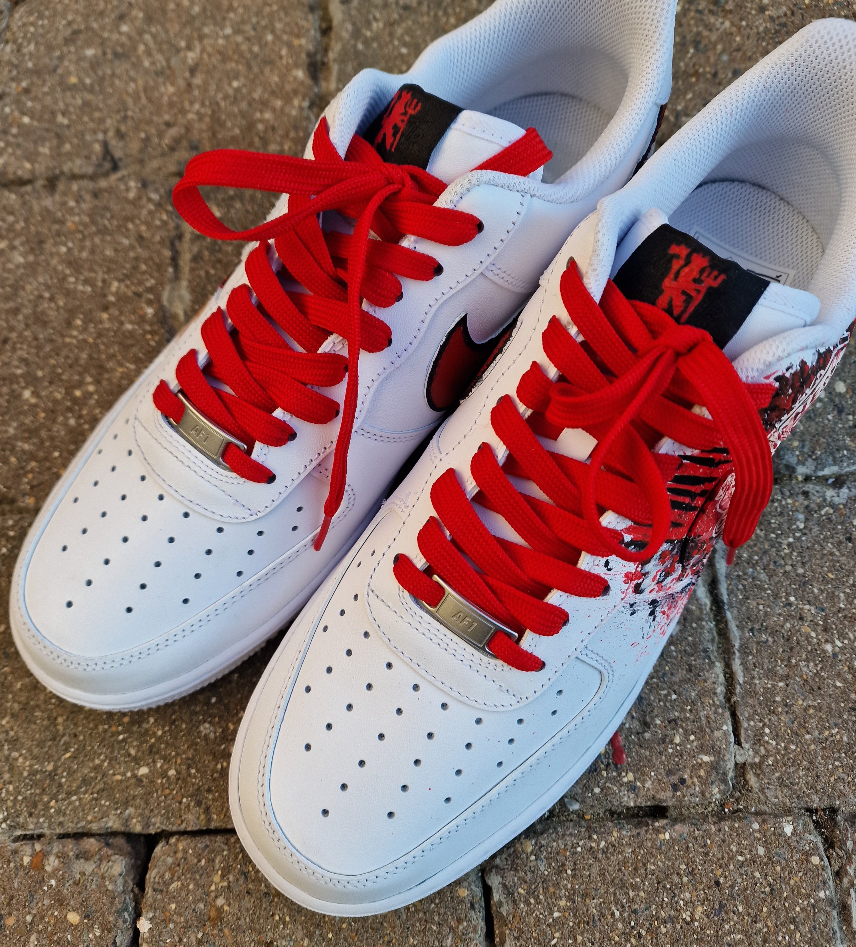 "Custom hand-painted Nike Air Force 1 sneakers featuring Manchester United and Portugal national football team crests, splattered in bold red, green, and black paint with unique details, crafted by Gitartsy."


