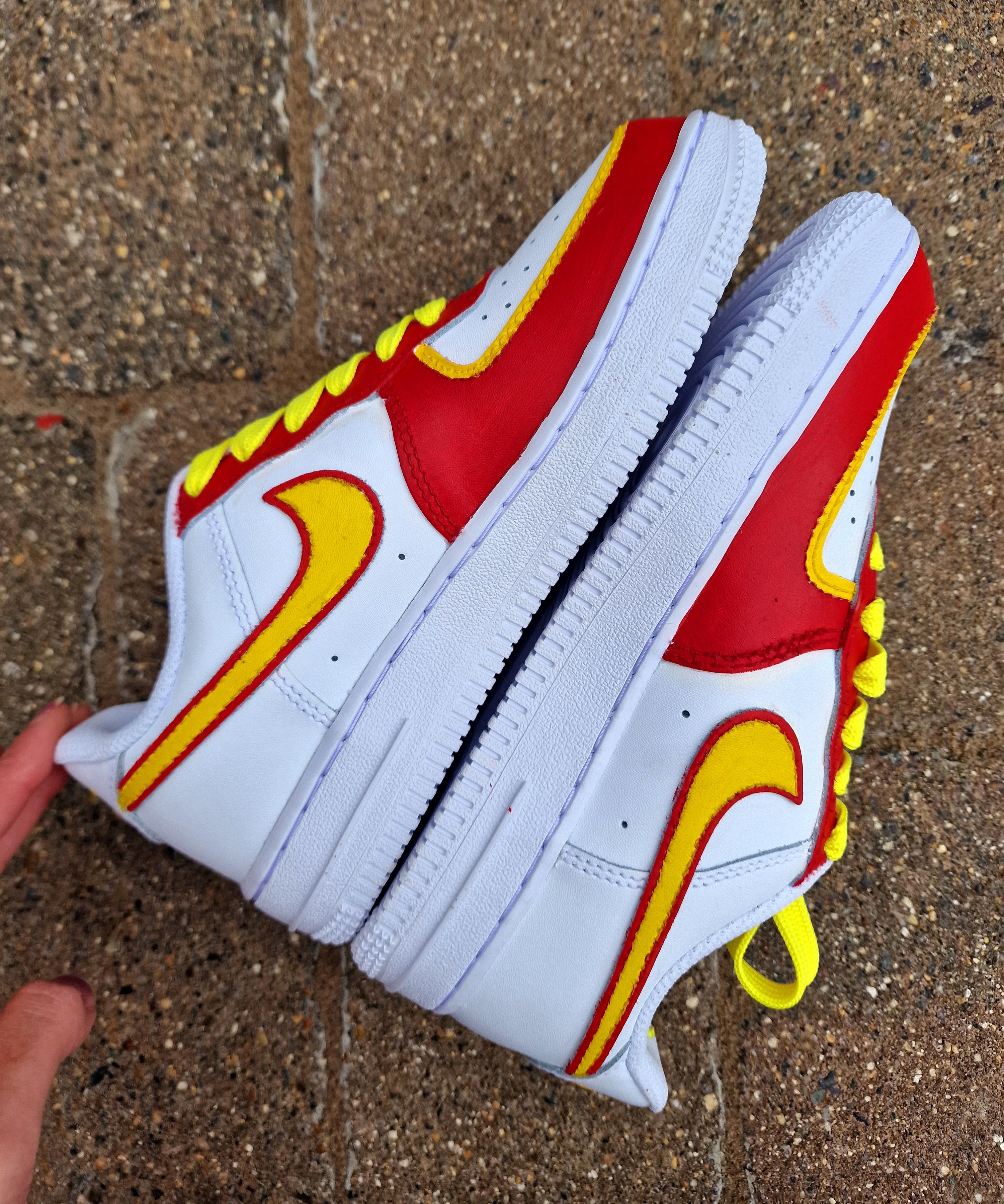 Hand-painted custom sneakers featuring the Manchester United crest, Marcus Rashford kit illustration, and personalized details on a red, yellow, and white theme; perfect for football fans.

