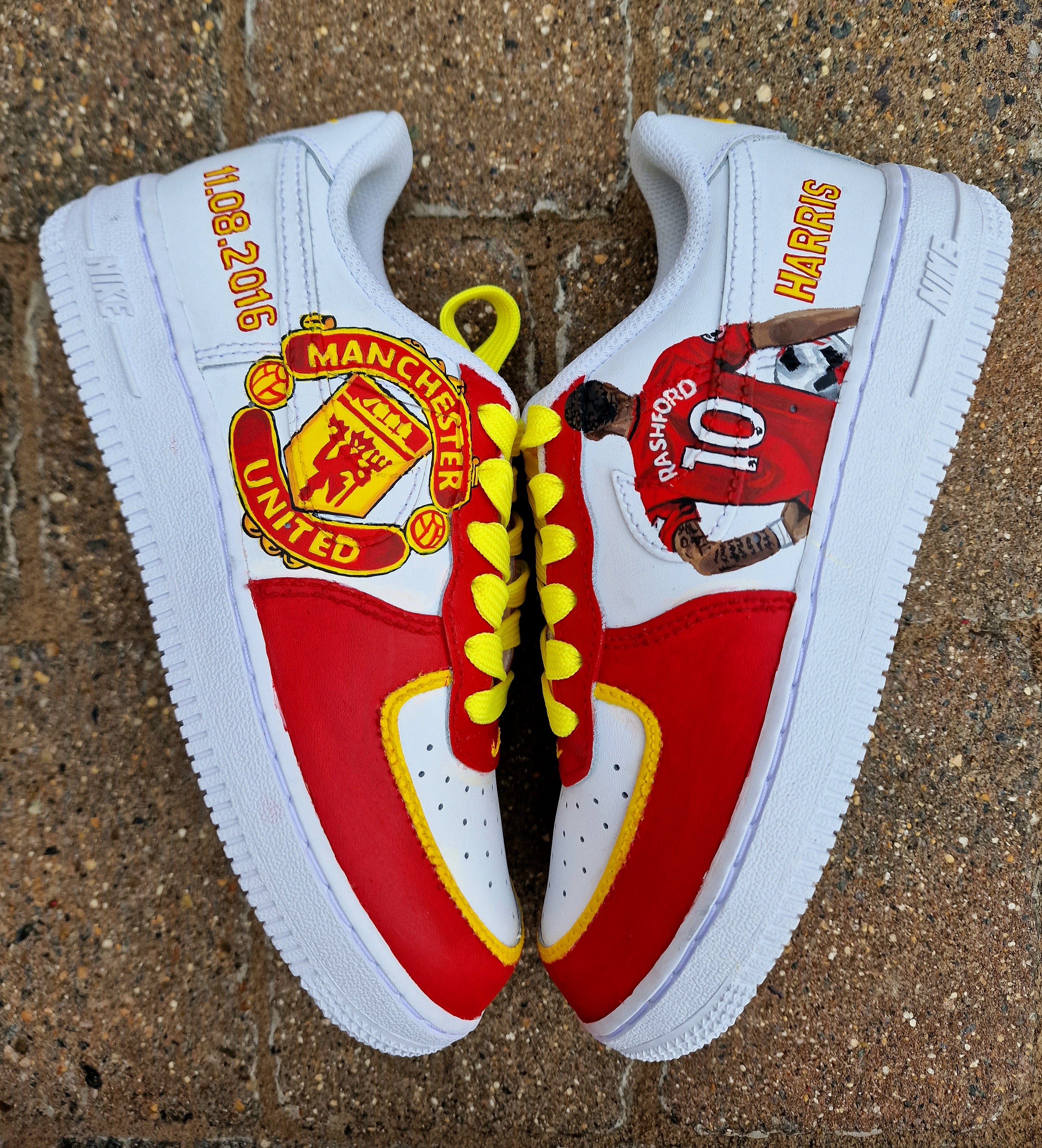 Hand-painted custom sneakers featuring the Manchester United crest, Marcus Rashford kit illustration, and personalized details on a red, yellow, and white theme; perfect for football fans.

