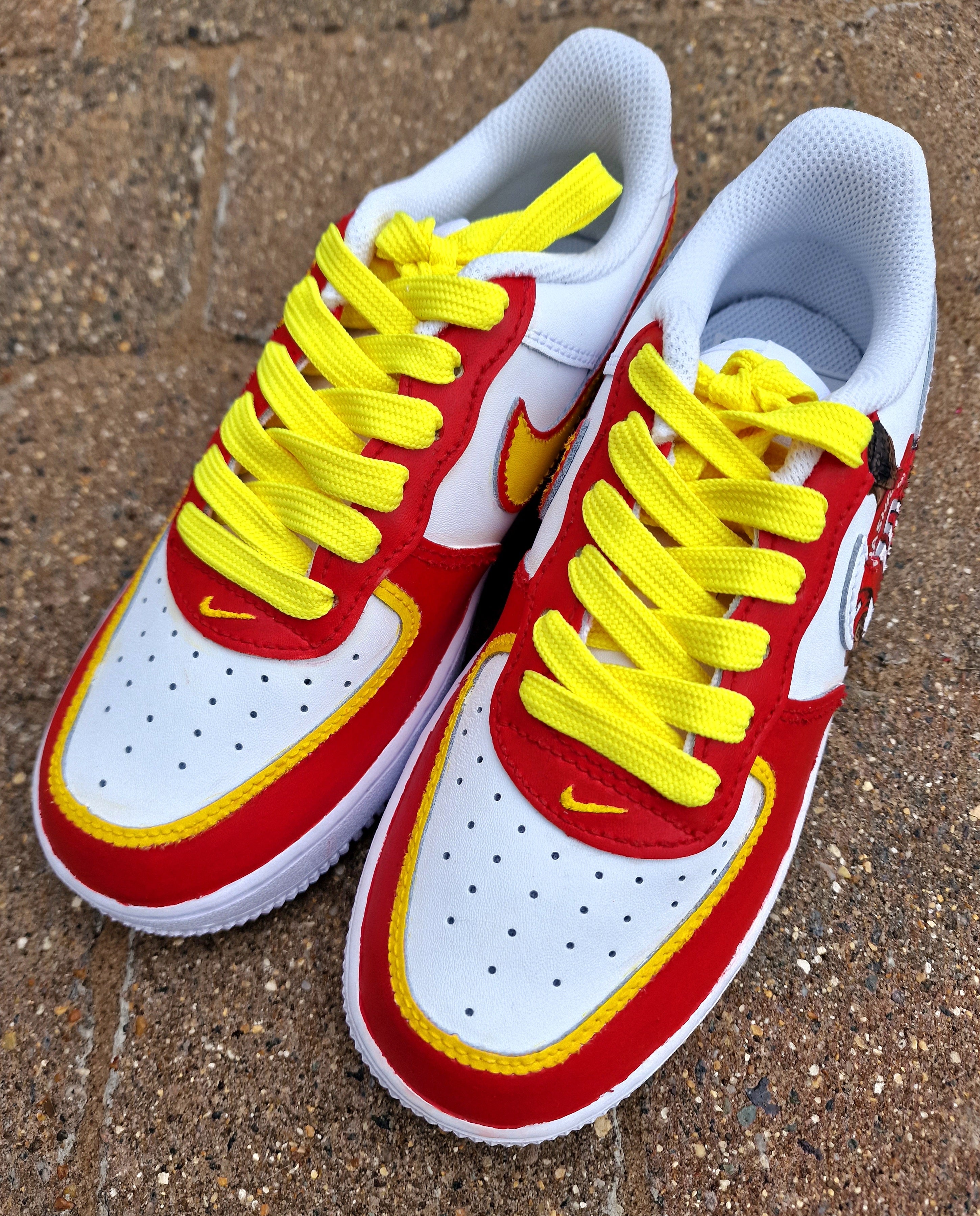 Hand-painted custom sneakers featuring the Manchester United crest, Marcus Rashford kit illustration, and personalized details on a red, yellow, and white theme; perfect for football fans.

