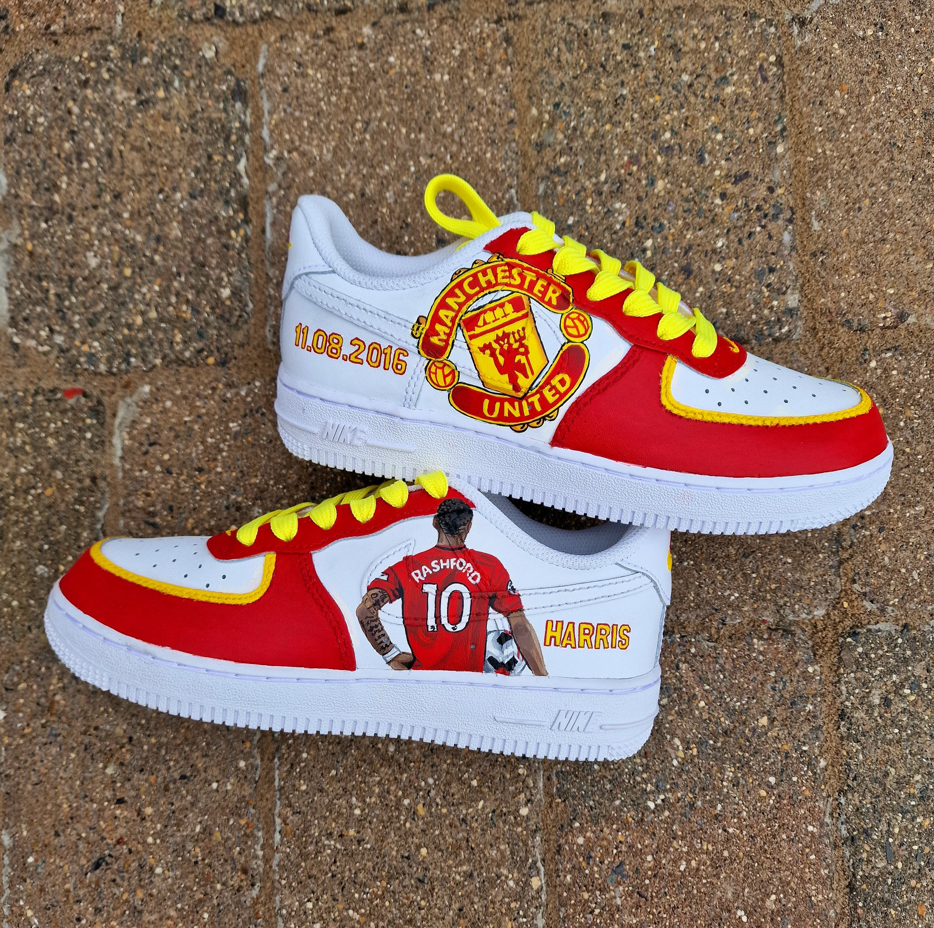 Hand-painted custom sneakers featuring the Manchester United crest, Marcus Rashford kit illustration, and personalized details on a red, yellow, and white theme; perfect for football fans.

