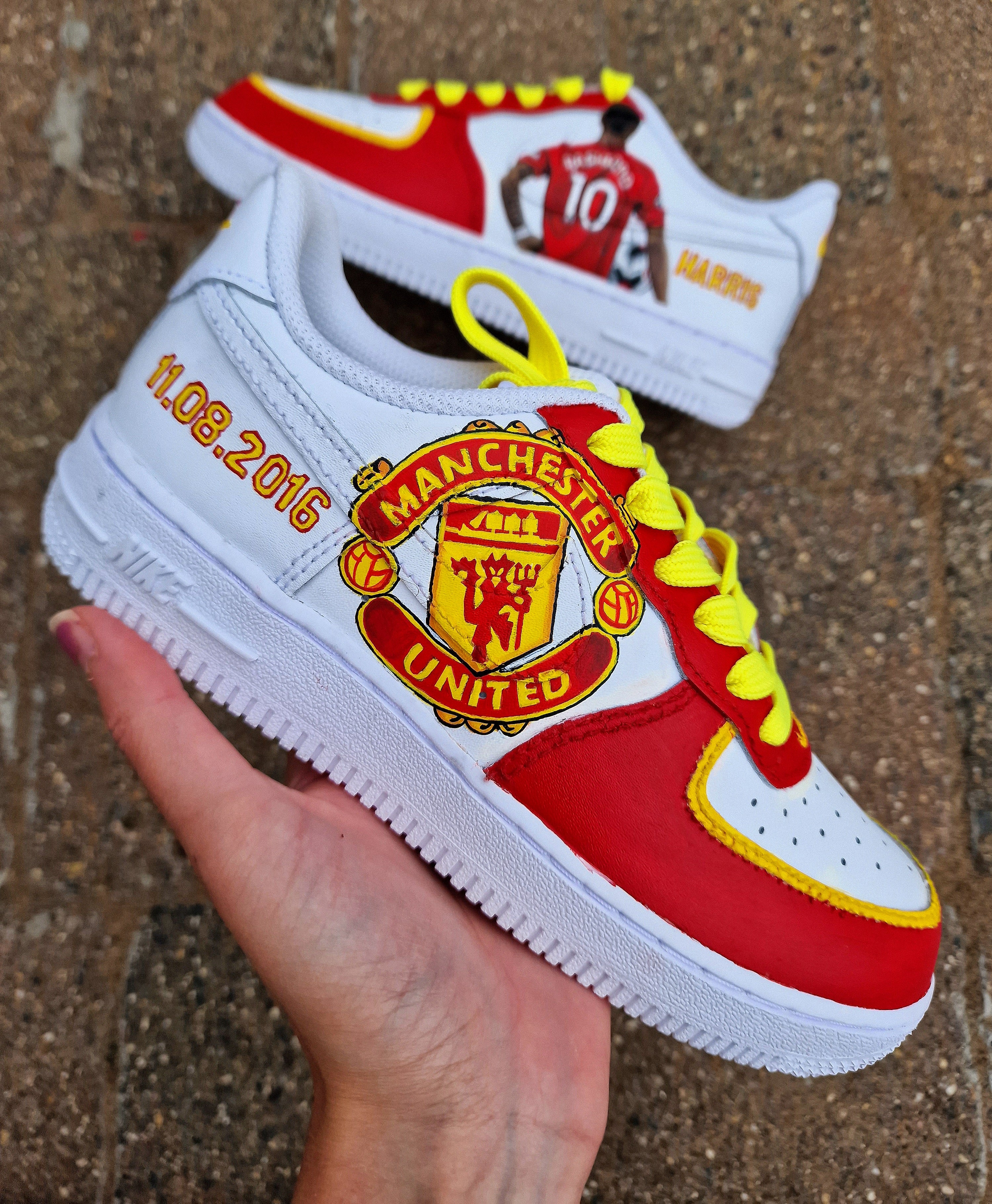Hand-painted custom sneakers featuring the Manchester United crest, Marcus Rashford kit illustration, and personalized details on a red, yellow, and white theme; perfect for football fans.

