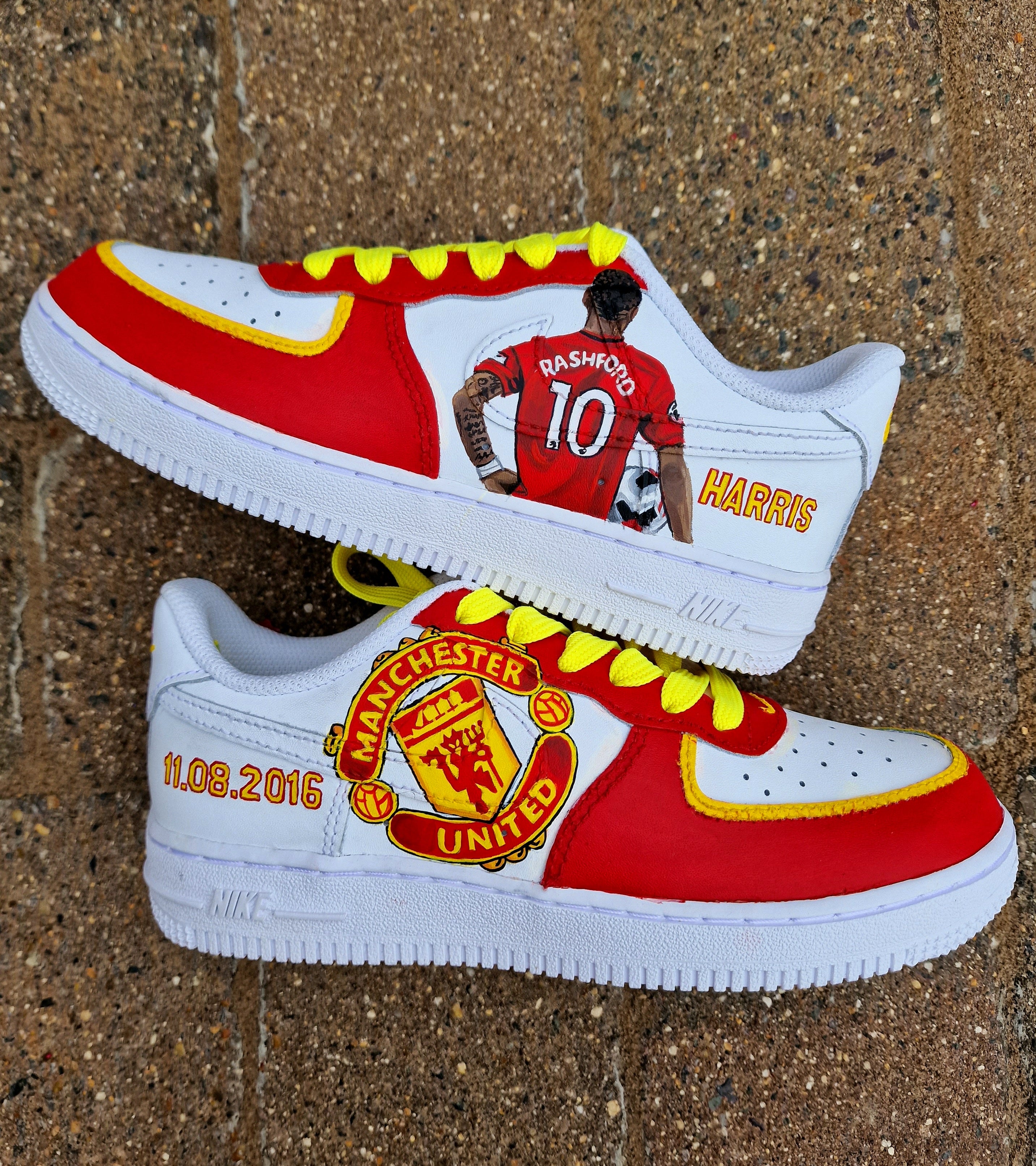 Hand-painted custom sneakers featuring the Manchester United crest, Marcus Rashford kit illustration, and personalized details on a red, yellow, and white theme; perfect for football fans.

