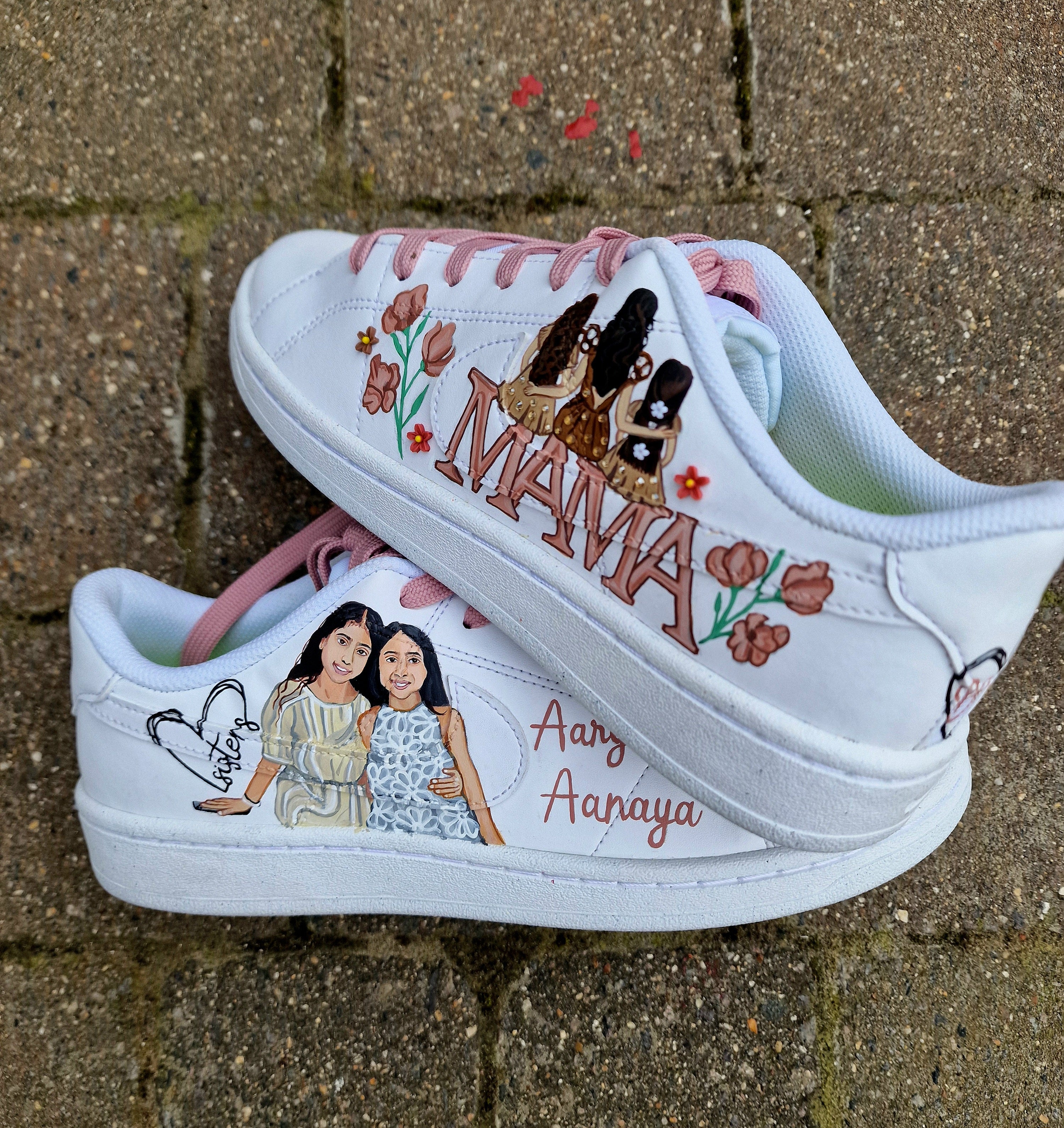 Custom hand-painted Nike sneakers featuring a realistic portrait of a mother and her daughters, personalized names, floral details, and loving elements like “Mama” and “Ba.” Crafted in white leather with pink swooshes and laces, these shoes are a perfect Mother’s Day gift showcasing unique wearable art.

