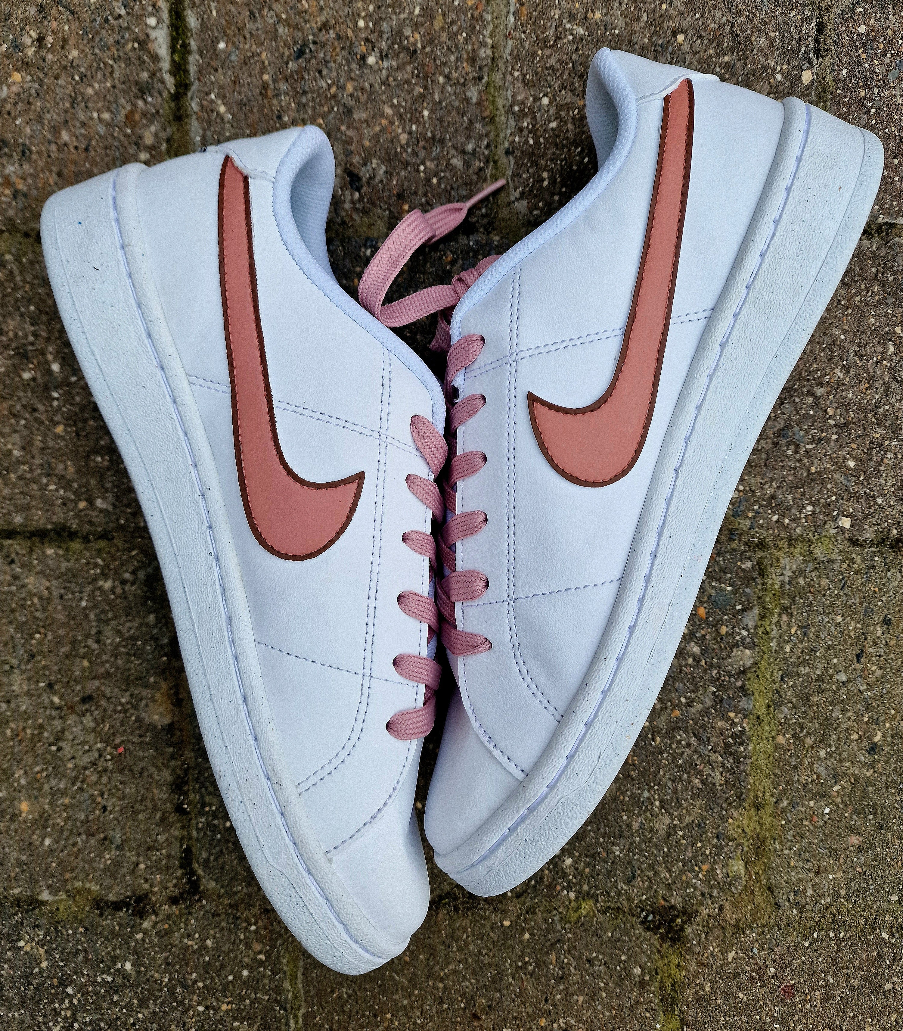 Custom hand-painted Nike sneakers featuring a realistic portrait of a mother and her daughters, personalized names, floral details, and loving elements like “Mama” and “Ba.” Crafted in white leather with pink swooshes and laces, these shoes are a perfect Mother’s Day gift showcasing unique wearable art.

