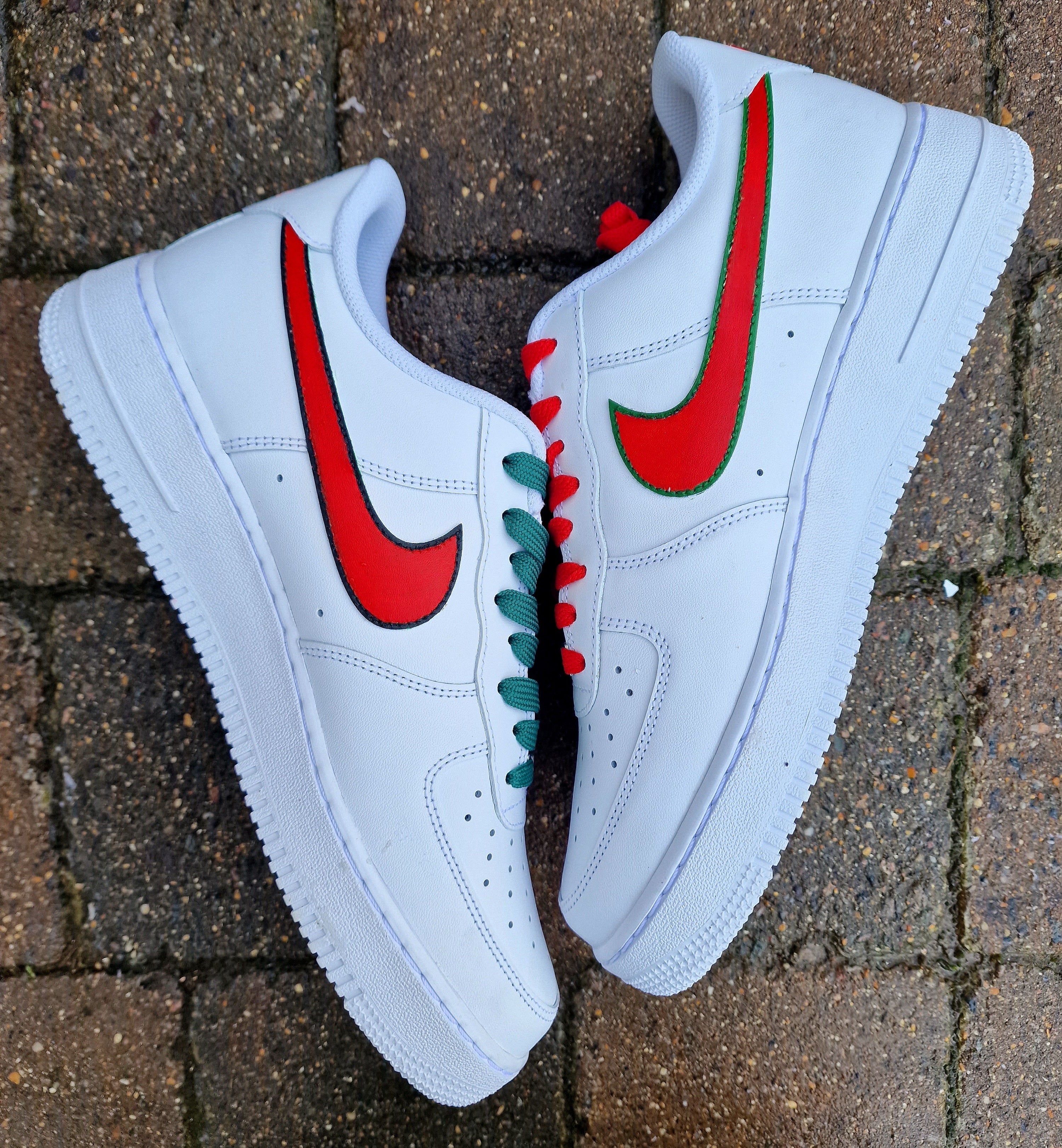 "Custom hand-painted Nike Air Force 1 sneakers featuring Manchester United and Portugal national football team crests, splattered in bold red, green, and black paint with unique details, crafted by Gitartsy."

