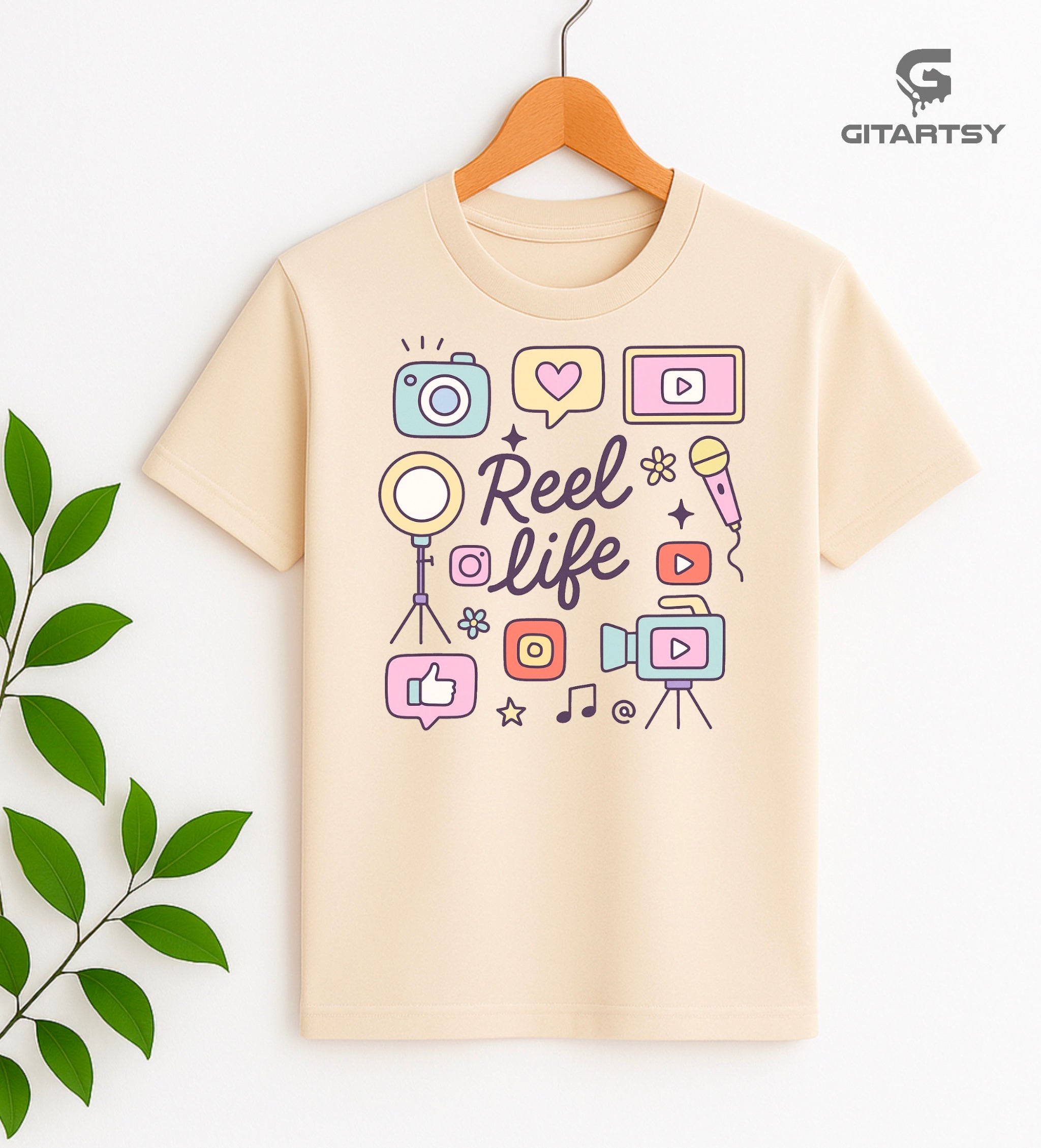 Pastel “Reel Life” T-shirt with social media icons, camera, microphone, and content creator doodles – ideal for influencers, vloggers, and content creators