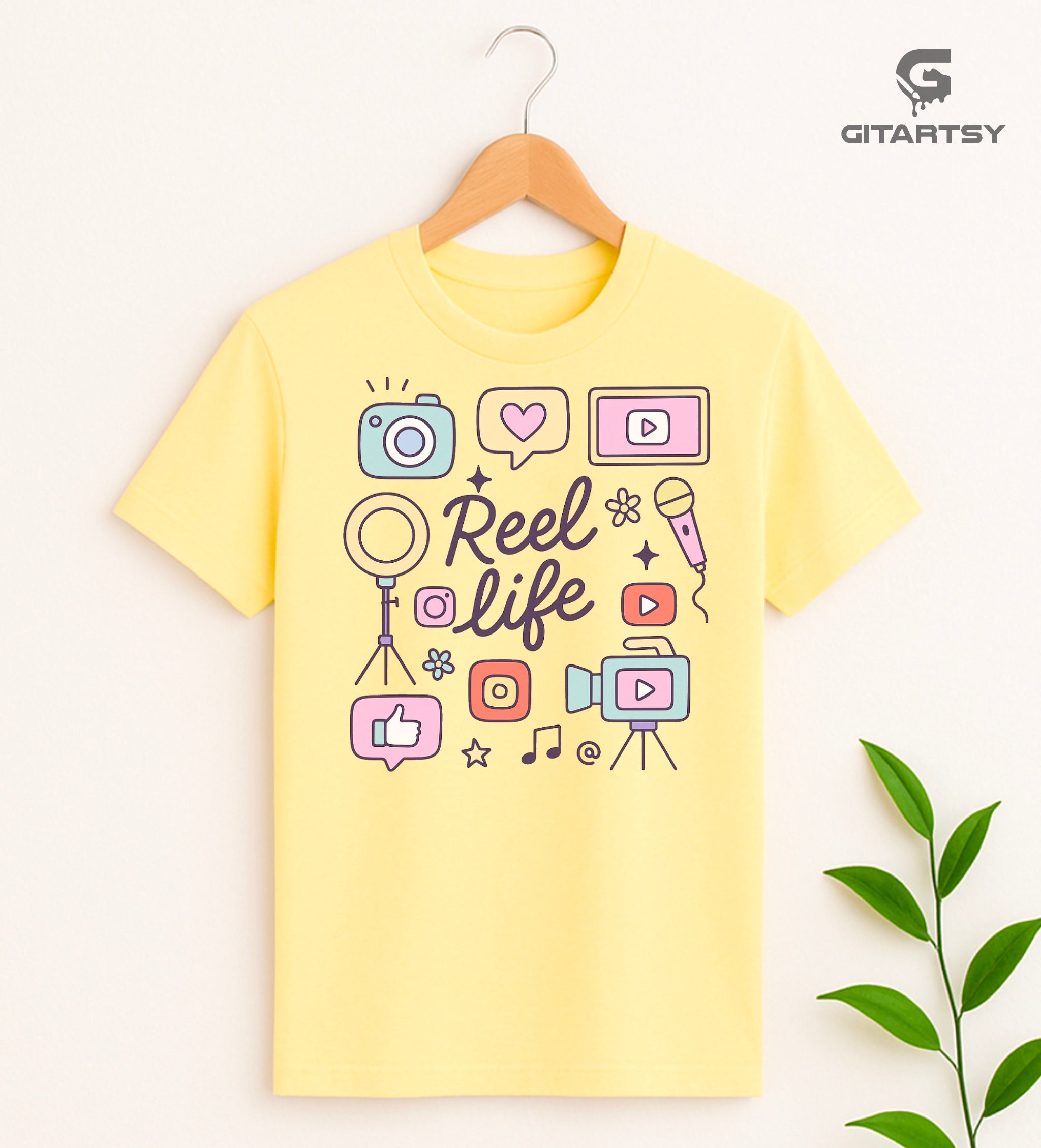Pastel “Reel Life” T-shirt with social media icons, camera, microphone, and content creator doodles – ideal for influencers, vloggers, and content creators
