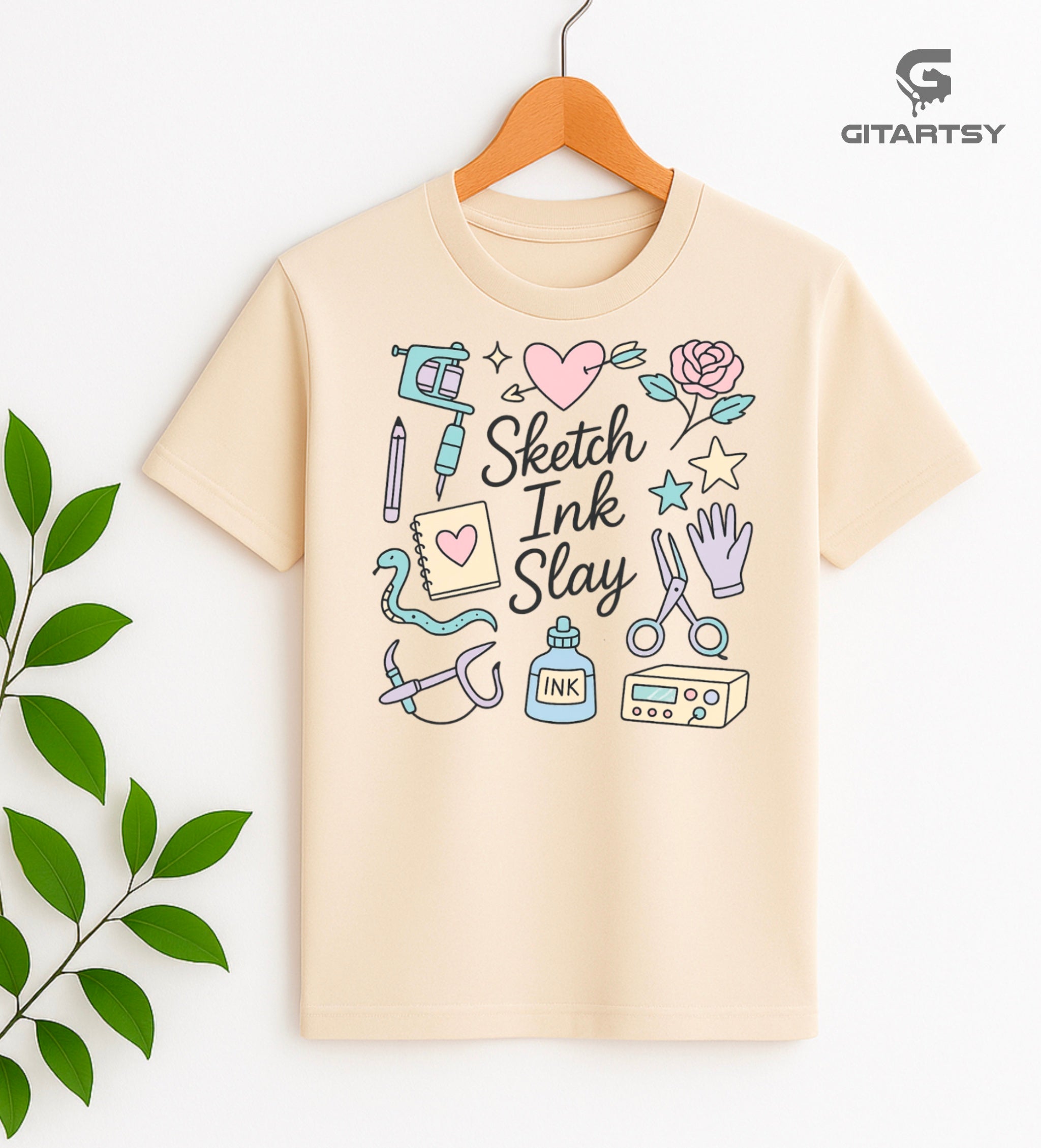 T-shirt for tattoo artists featuring pastel illustrations of tattoo machines, ink, sketchpad, and "Sketch Ink Slay" text