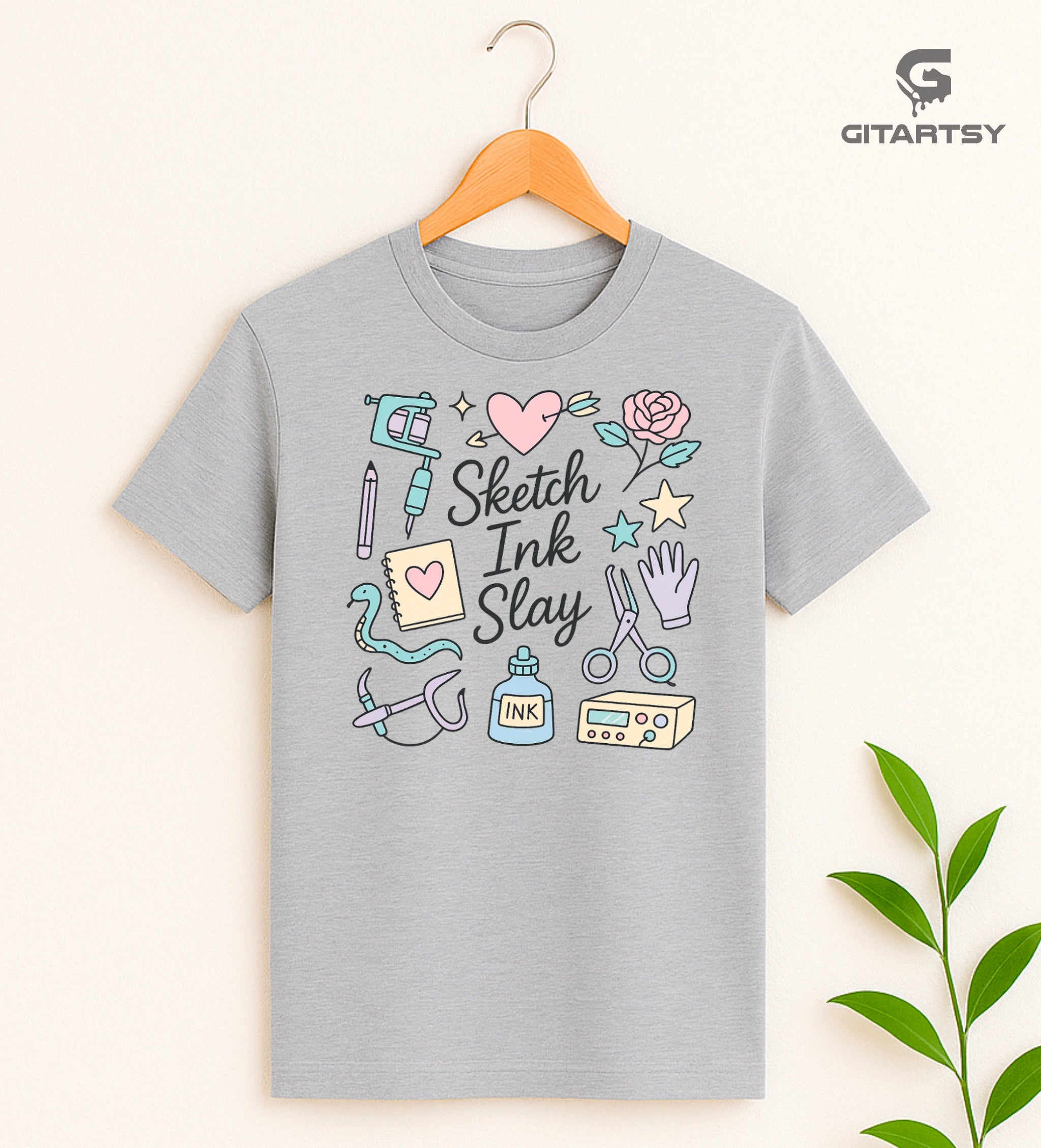 T-shirt for tattoo artists featuring pastel illustrations of tattoo machines, ink, sketchpad, and "Sketch Ink Slay" text