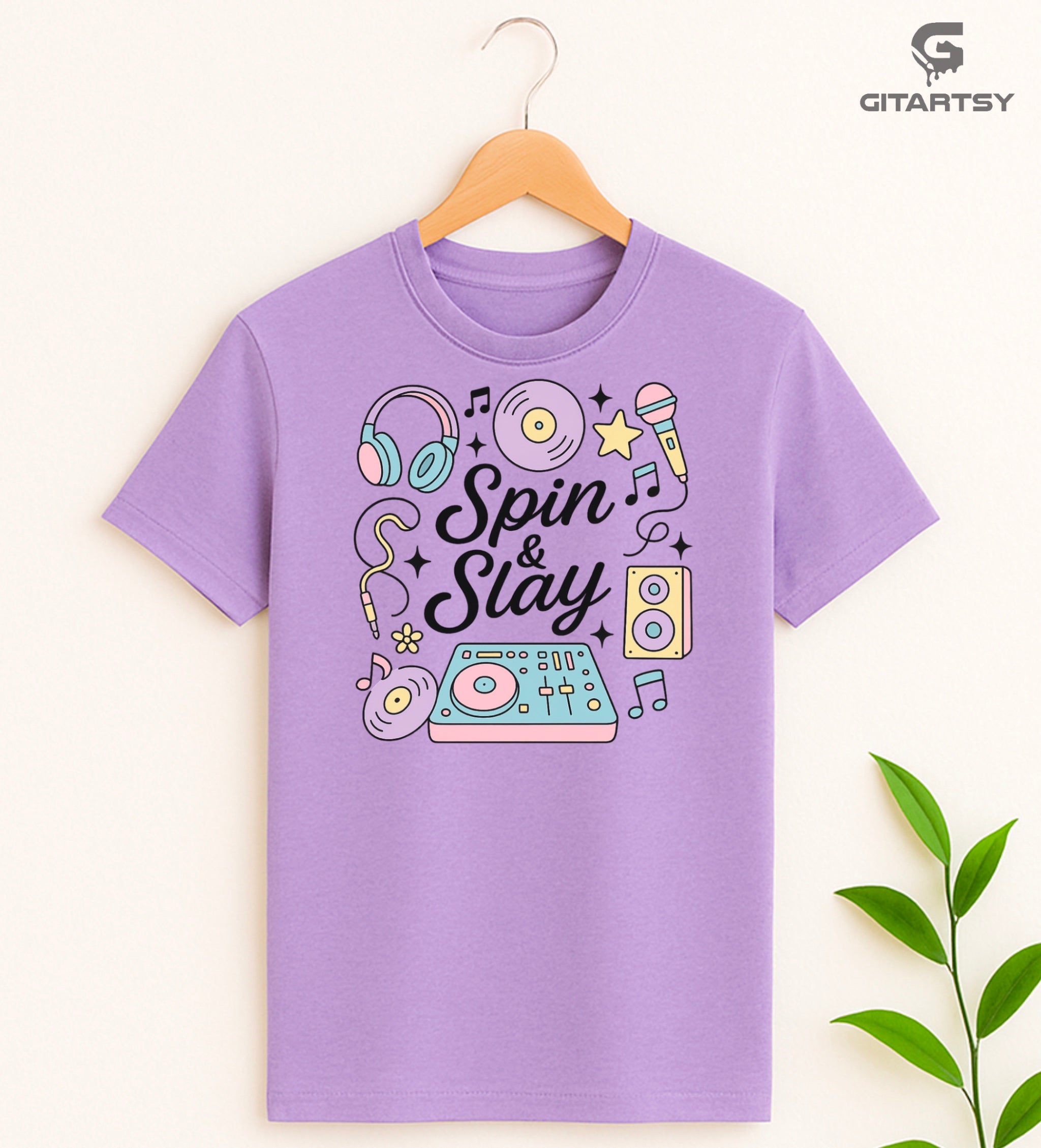 Pastel “Spin & Slay” DJ-themed T-shirt with illustrations of headphones, turntable, vinyl, mic, and speakers – ideal for DJs and music producers.