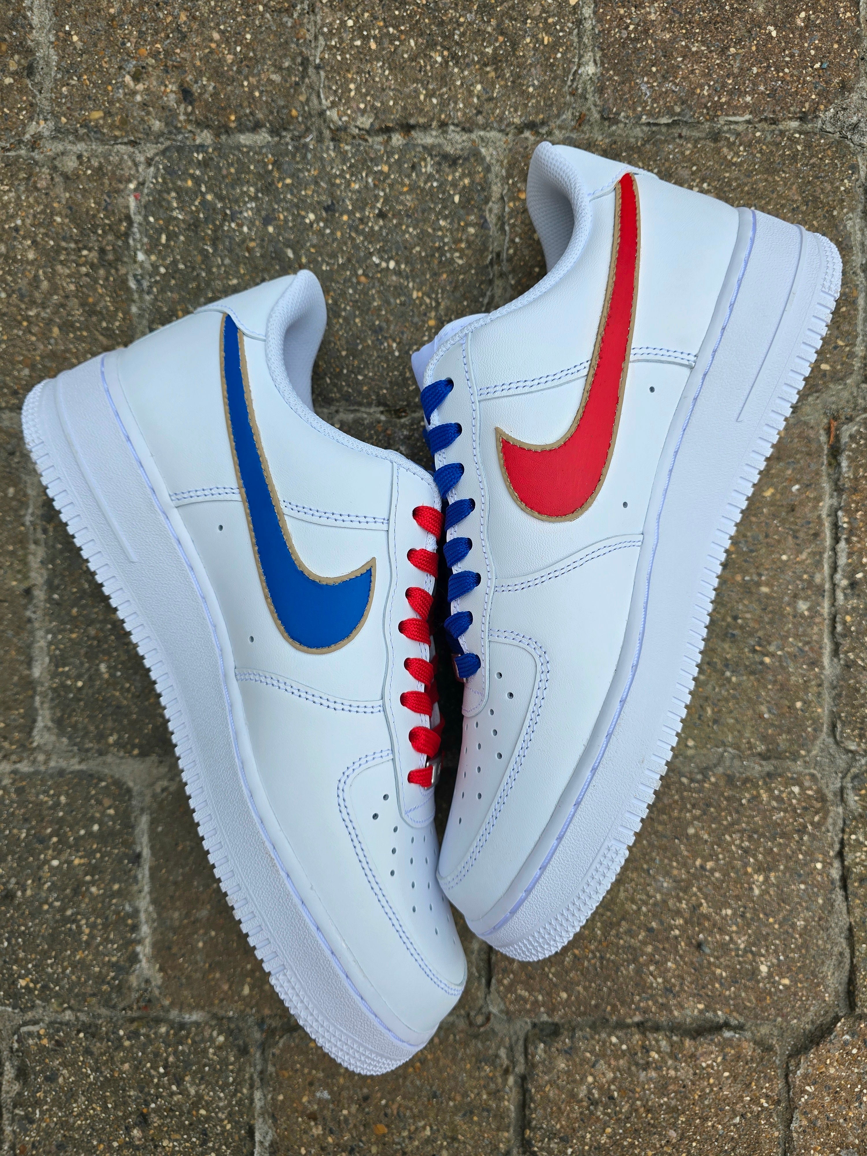 White sneakers with colorful Nike logos on a brick surface